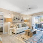 Two-BR Apartments in Palm Bay FL - Meri Palm Bay - Living Room with Couch, Floor Lamps, Coffee Table, Area Rug, Ceiling Fan, Tile Flooring and Large Sliding Glass Door to Patio.