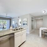 Kitchen with tile flooring, stainless steel appliances, granite countertops, dual sink, designer lighting, and open access to dining room and living room