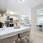 Dining room with dinner table, seating, tile flooring, designer lighting, and open access to the kitchen and living room