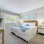 Bedroom with carpet flooring, designer and natural lighting, lamps, and plant decor